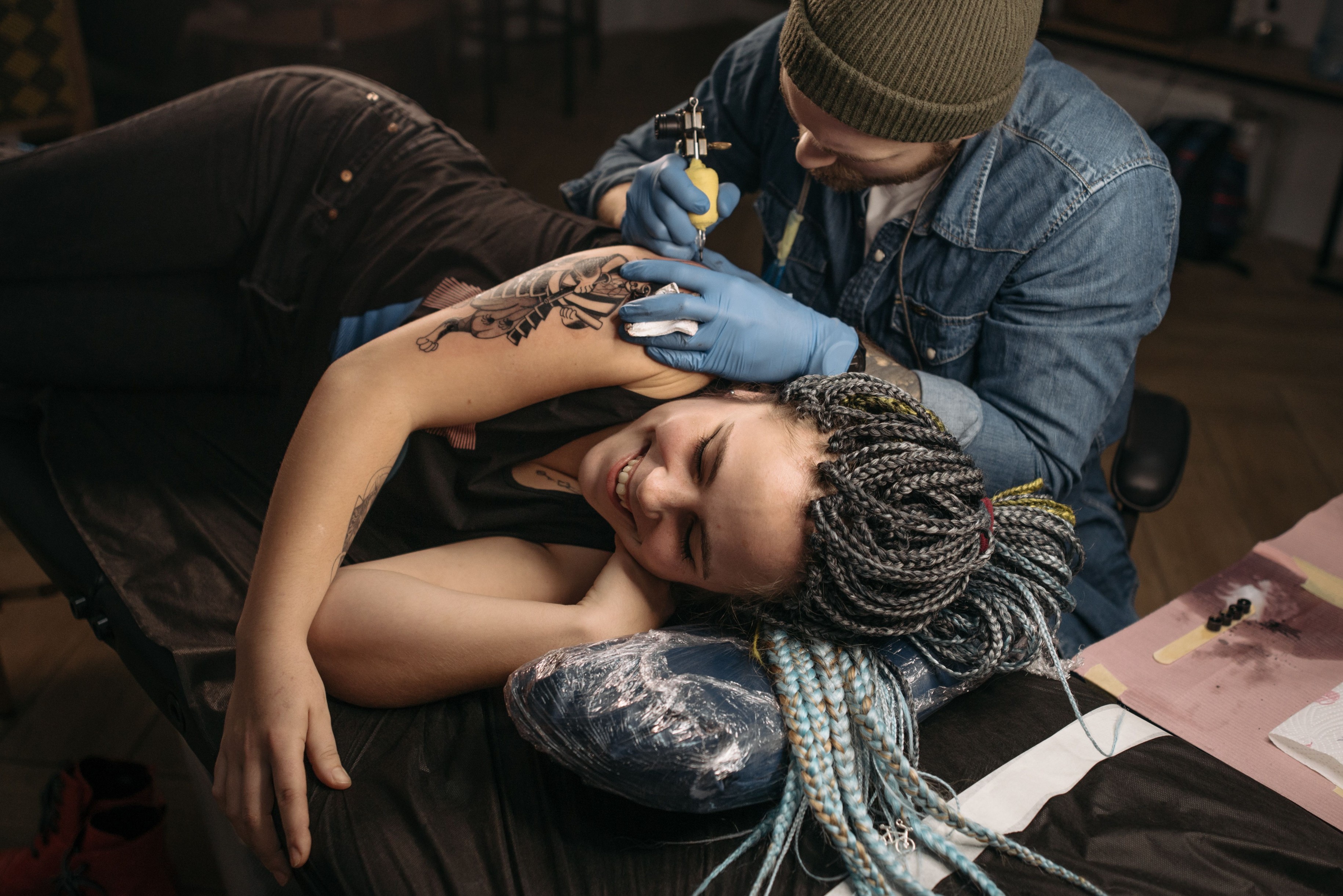 A Wame Ink artist outlining a neo-traditional piece on a client's upper arm.